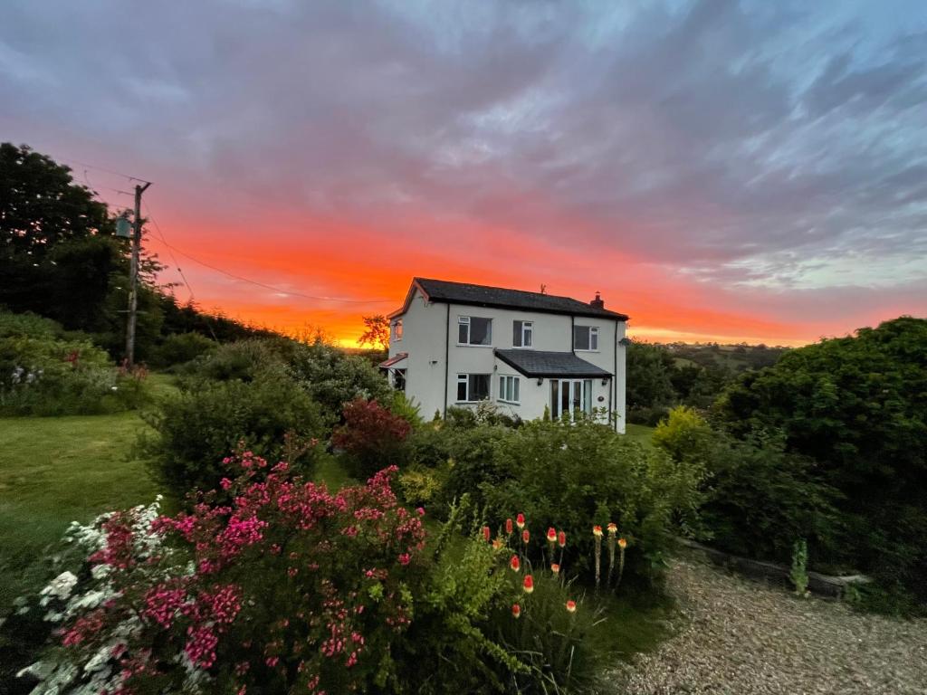 een huis op een heuvel met een zonsondergang op de achtergrond bij Country Home with Gardens in Newtown