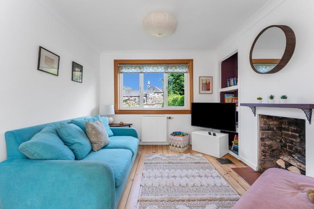 sala de estar con sofá azul y chimenea en Cozy with Character Cheerful Home with Garden at Leith Links Park, en Edimburgo