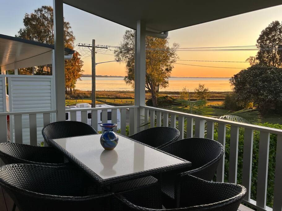 a table and chairs on a porch with a view of the ocean at Lakeview House LILAC in Chittaway Point