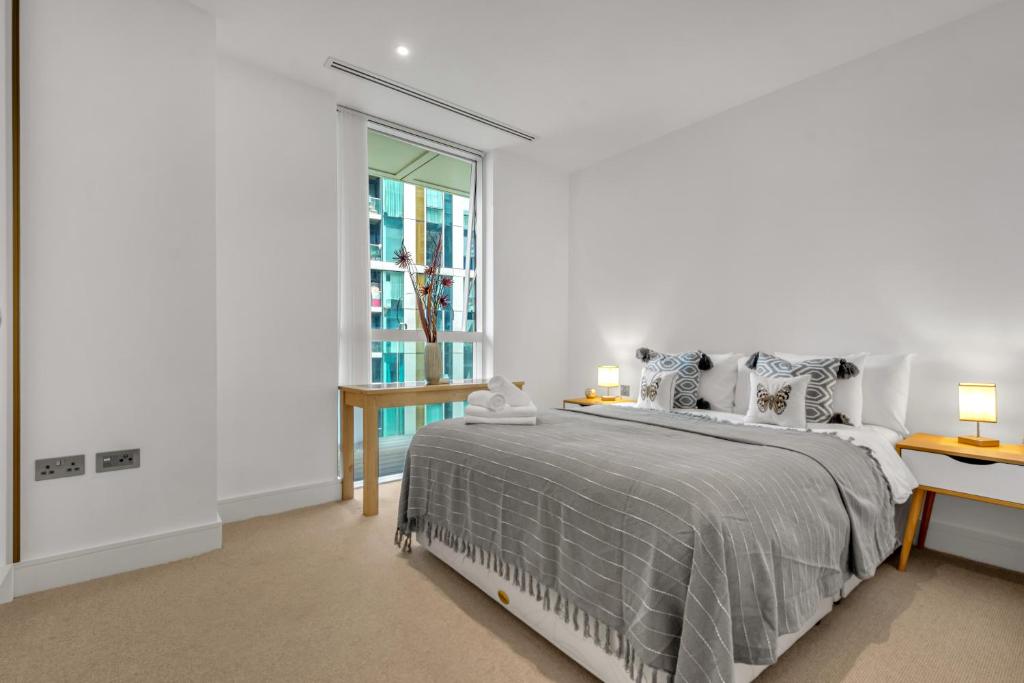 a white bedroom with a bed and a window at Modern 01 & 02 Bed Apartment in Canary Wharf in London