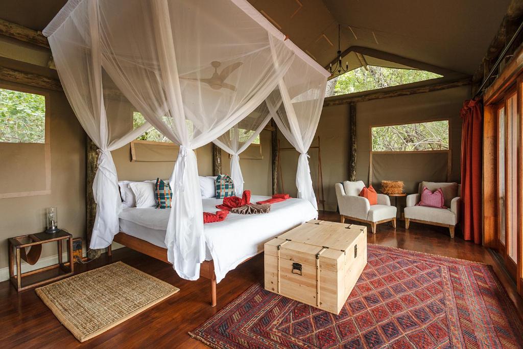 Amber River Camp في Okavango Delta: غرفة نوم بسرير مع مظلة