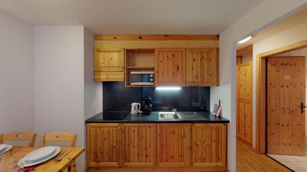 a kitchen with wooden cabinets and a sink at Pracondu OUTDOOR & FUN appartement 8 personnes by Alpvision Résidences in Nendaz