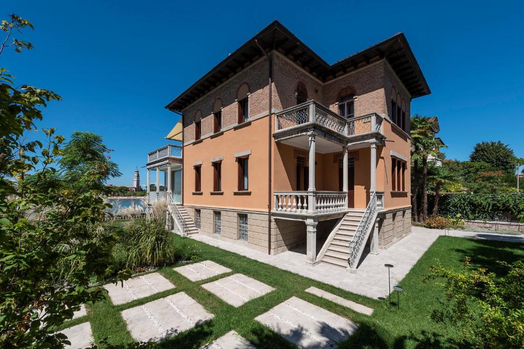 a large brick house with a balcony and a yard at Ca' delle Contesse - Villa on lagoon with private dock and spectacular view in Venice-Lido