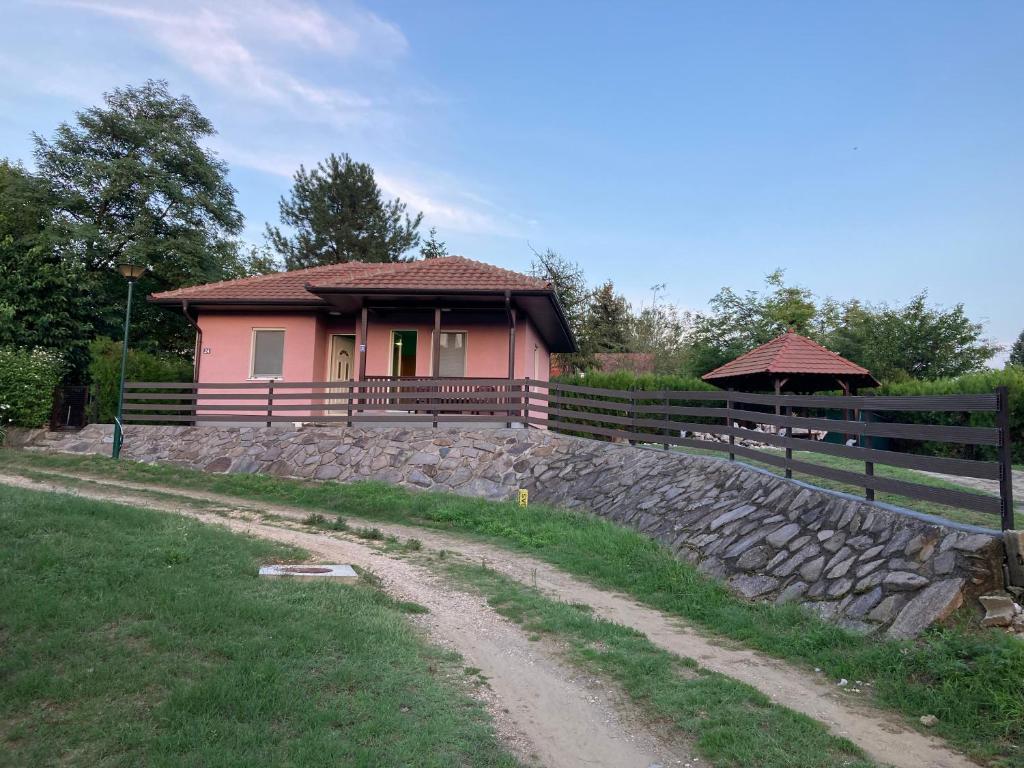ein kleines rosafarbenes Haus mit einer steinernen Wand in der Unterkunft Katina vikendica in Veliko Gradište