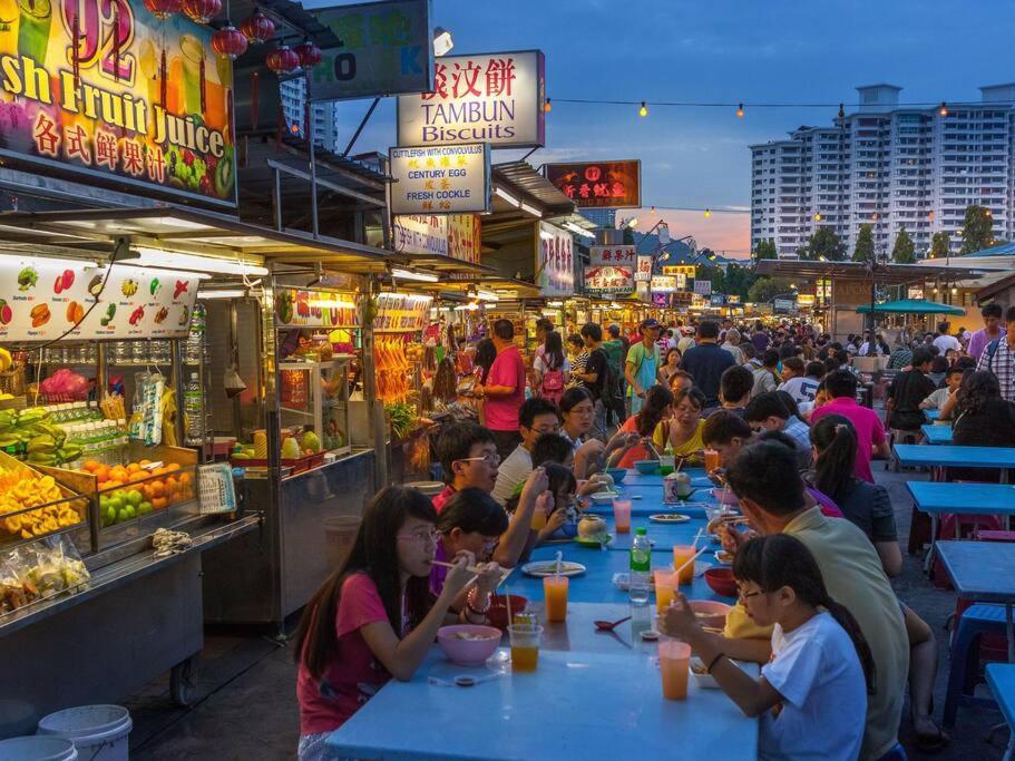 un grupo de personas sentadas en mesas comiendo comida en un mercado en Tanjung Bungah PEARL HILL42 Homestay en Tanjung Bungah