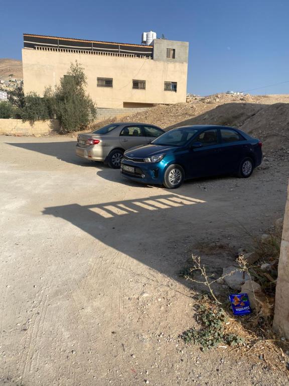 two cars parked in a parking lot in front of a building at Hustle's look in Wadi Musa