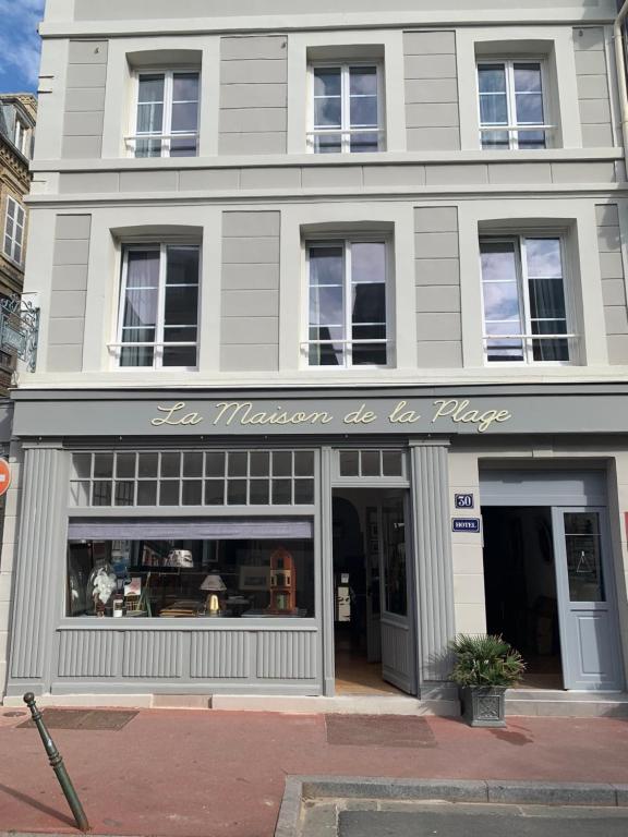 una tienda frente a un edificio con un cartel. en La Maison de la Plage, en Trouville-sur-Mer