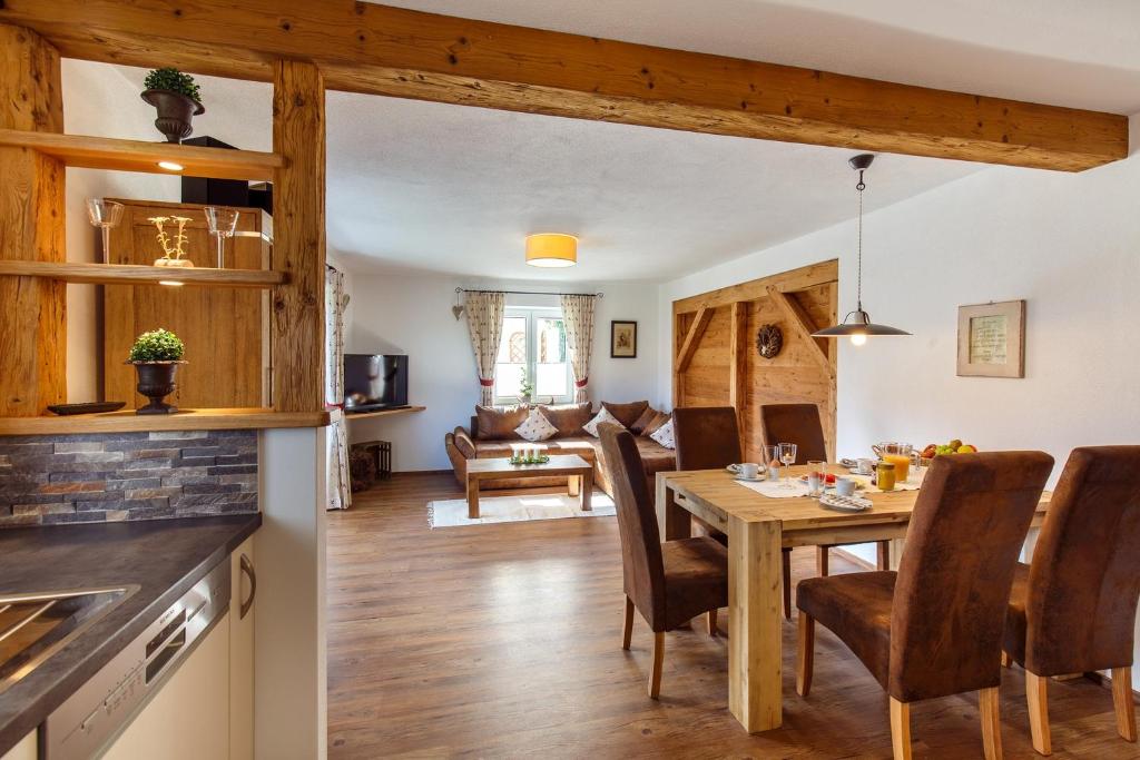 cocina y sala de estar con mesa de madera y sillas en Ferienwohnung Adlerhügel en Ruhpolding