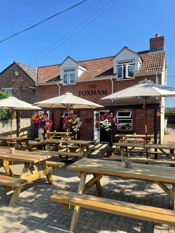 a group of wooden picnic tables in front of a building at The Foxham in Chippenham