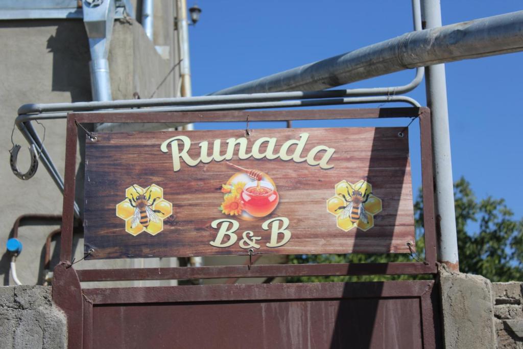 a wooden sign for a restaurant with a sign for at Runada B&B in Sisian