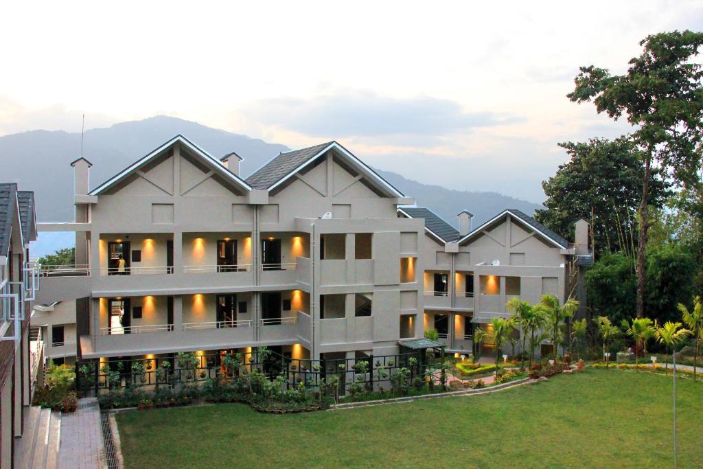 a large white building with mountains in the background at Sinclairs Retreat Kalimpong in Kalimpong