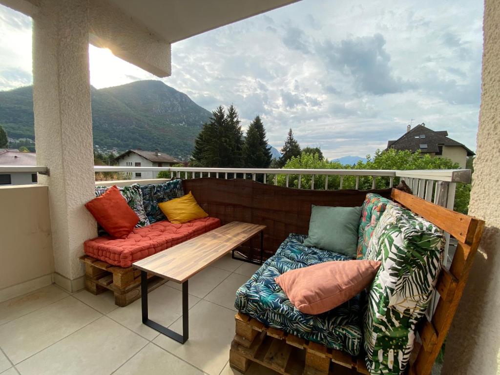 - un balcon avec deux canapés et une table avec des oreillers dans l'établissement Le Malaga - parking & balcon, à 500m du lac !, à Annecy