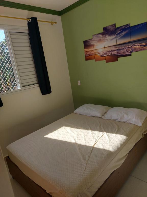 a bed in a green room with a window at Apartamento Resort Palmeiras 2 com 03 Quartos Ubatuba in Ubatuba