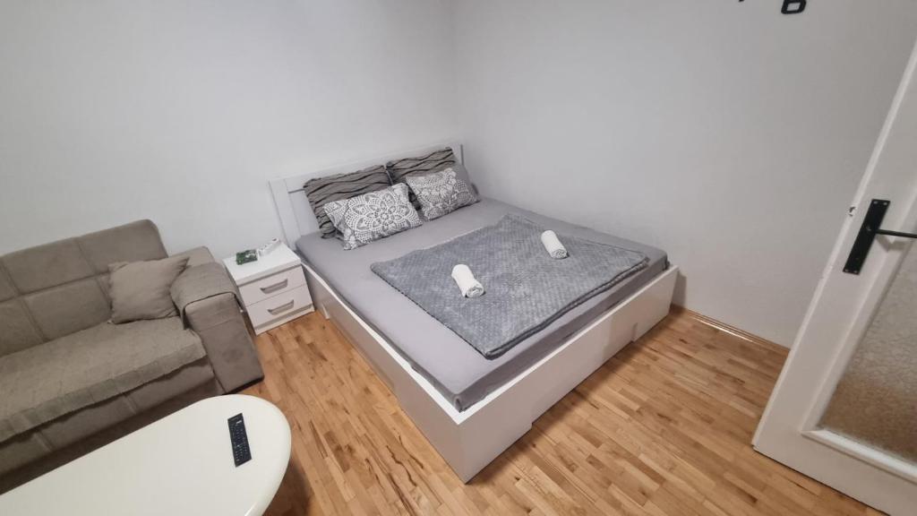 een kleine slaapkamer met een bed en een bank bij Stan na dan 50 BAM in Prijedor