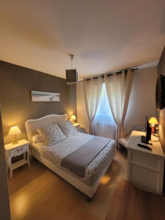 ein Schlafzimmer mit einem weißen Bett und einem Fenster in der Unterkunft Le Papé logement meublé tourisme 3 étoiles in Villers-sur-Mer