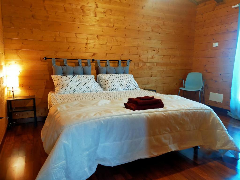 una camera da letto con un letto bianco con una parete di legno di Chalet Collalto con Piscina a Cerratina