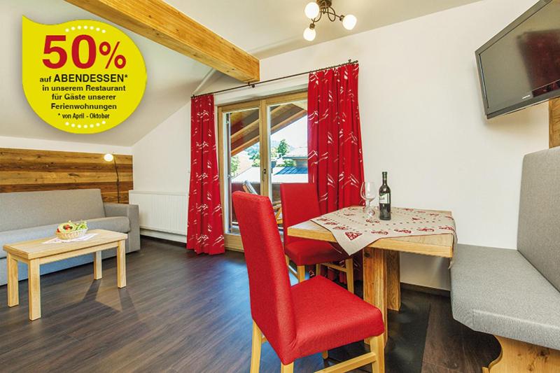 a living room with a table and red chairs at Zirbelstube in Reit im Winkl