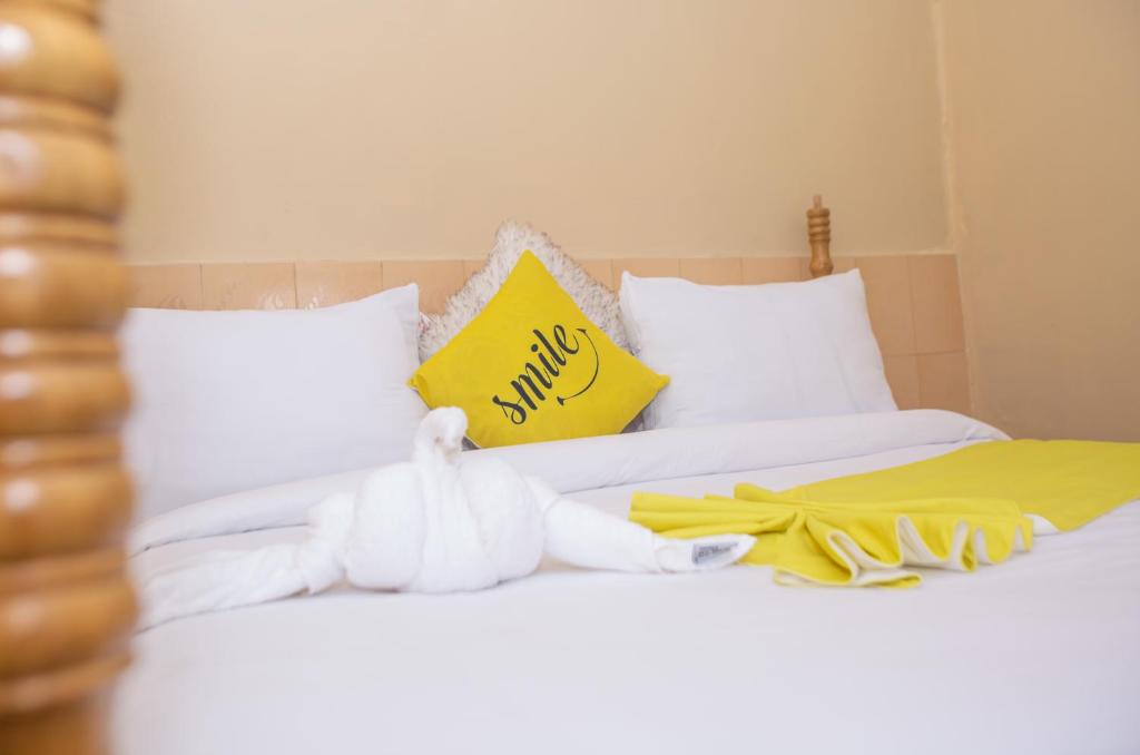 a bed with a yellow pillow and towels on it at The Nest Guest House in Kericho