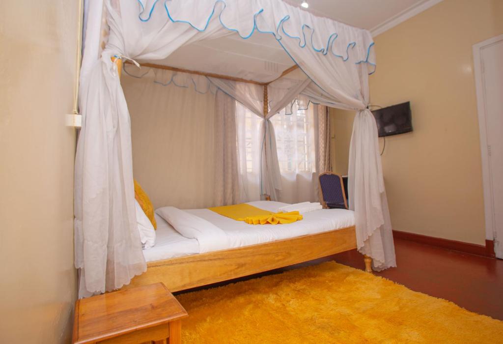 Bett mit Baldachin in einem Zimmer mit Fenster in der Unterkunft The Nest Guest House in Kericho