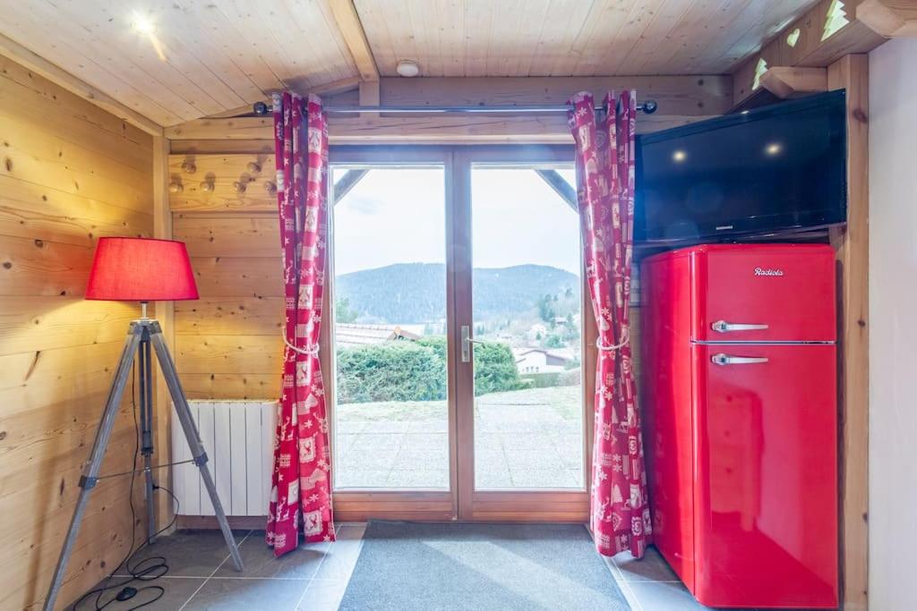 ジェラールメにあるAppart terrasse Vue Lacの赤い冷蔵庫と窓が備わる客室です。