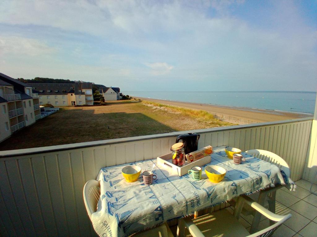 a table on a balcony with a view of the beach at DUPLEX les pieds dans l' eau in Jullouville-les-Pins