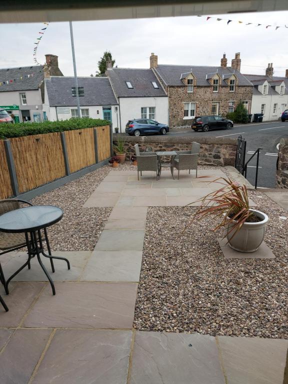 a patio with a table and chairs and buildings at No 2 New Buildings Morebattle in Morebattle