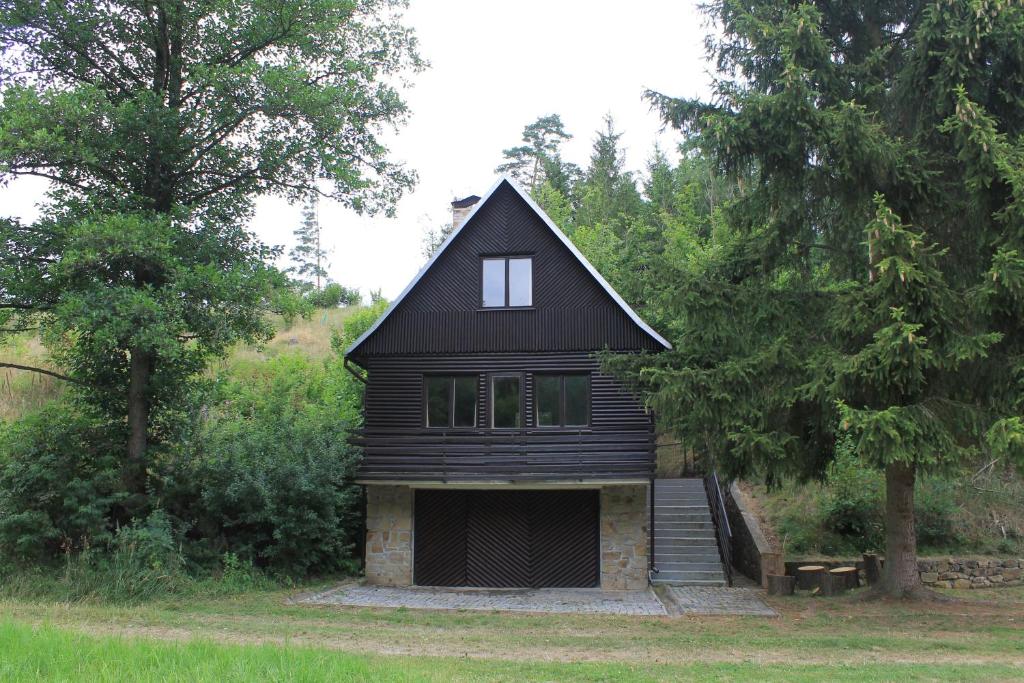 una casa negra con un garaje en el bosque en Chata Urbaneč, en Urbaneč