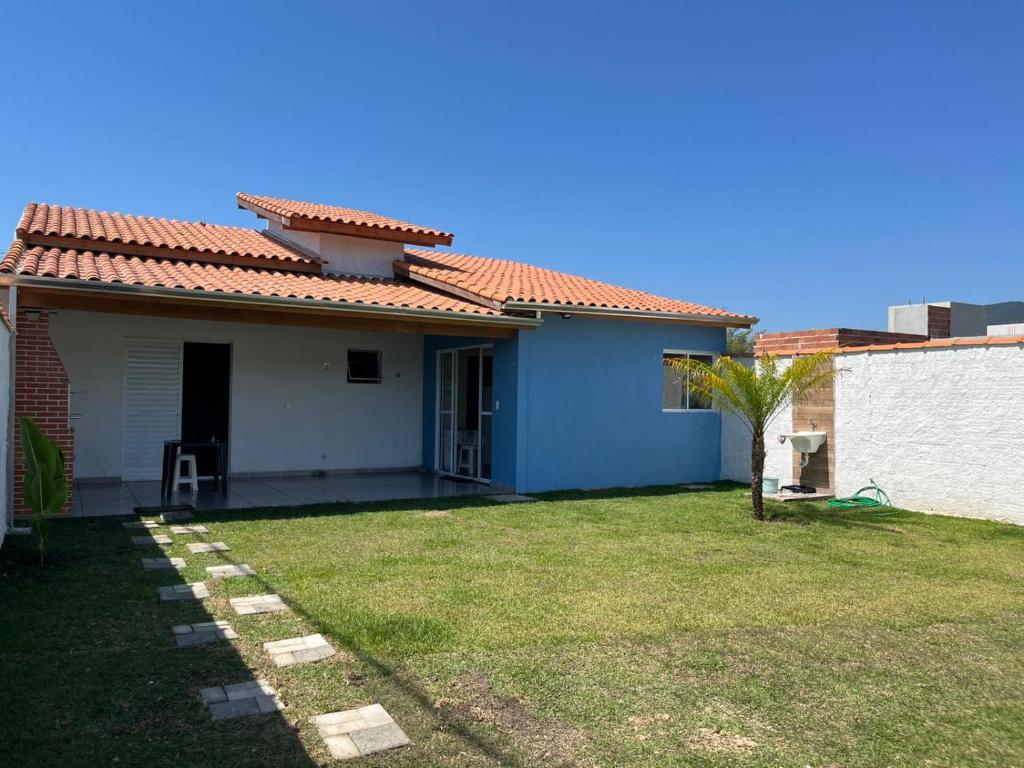 a blue and white house with a grass yard at Casa para aluguel de temporada em Caraguatatuba, ao lado de São Sebastião in Caraguatatuba