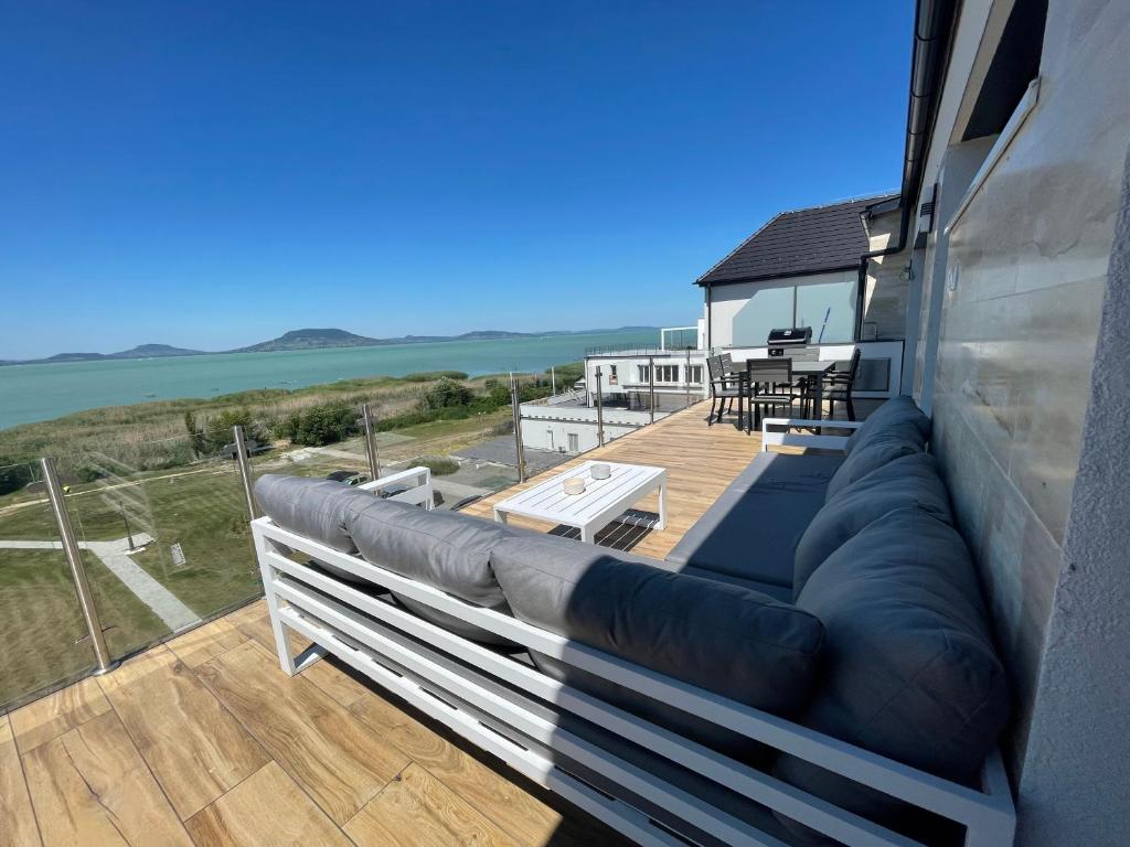 un sofá en un balcón con vistas al océano en Fenyves Beach Apartman en Balatonfenyves