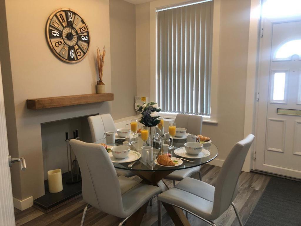 a dining room table with chairs and a clock on the wall at 2 Bedroom Luton Townhouse in Luton