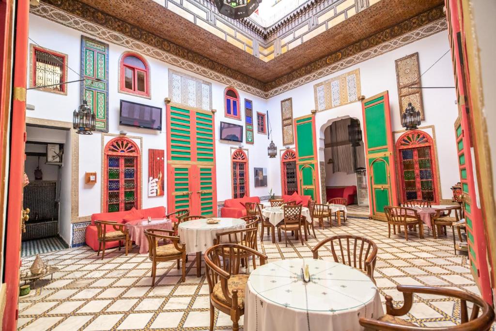 a restaurant with tables and chairs and colorful windows at Riad Haj Palace & Spa in Fez