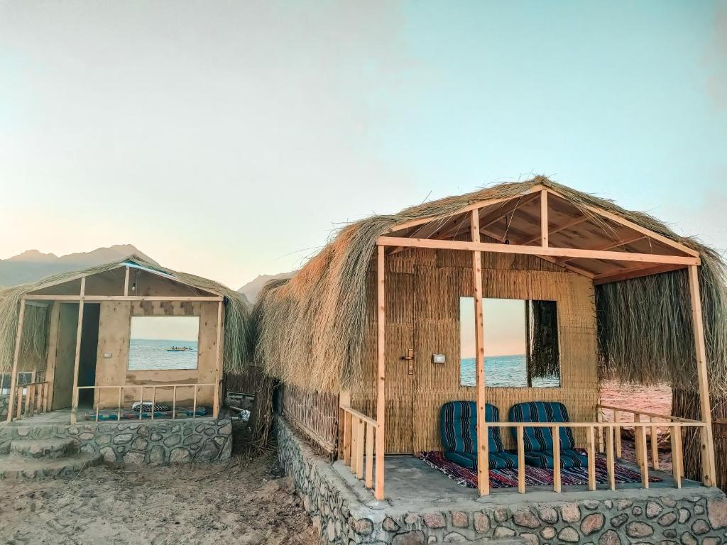Sinai Life Beach Camp في نويبع: كوخين على الشاطئ مع كراسي