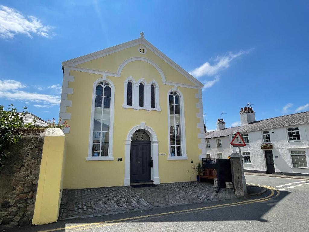 una chiesa gialla con una porta nera su una strada di Ty Biwmares a Beaumaris