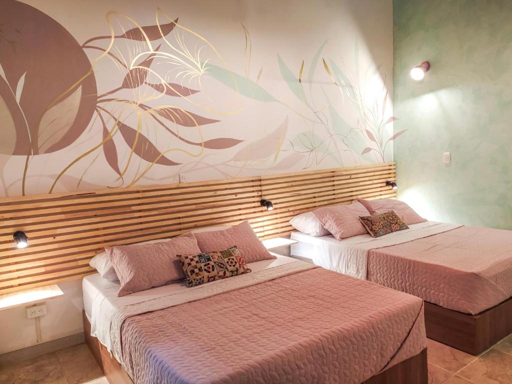 dwa łóżka w pokoju z malowidłem ściennym w obiekcie Neim Platinum Hotel w mieście Medellín
