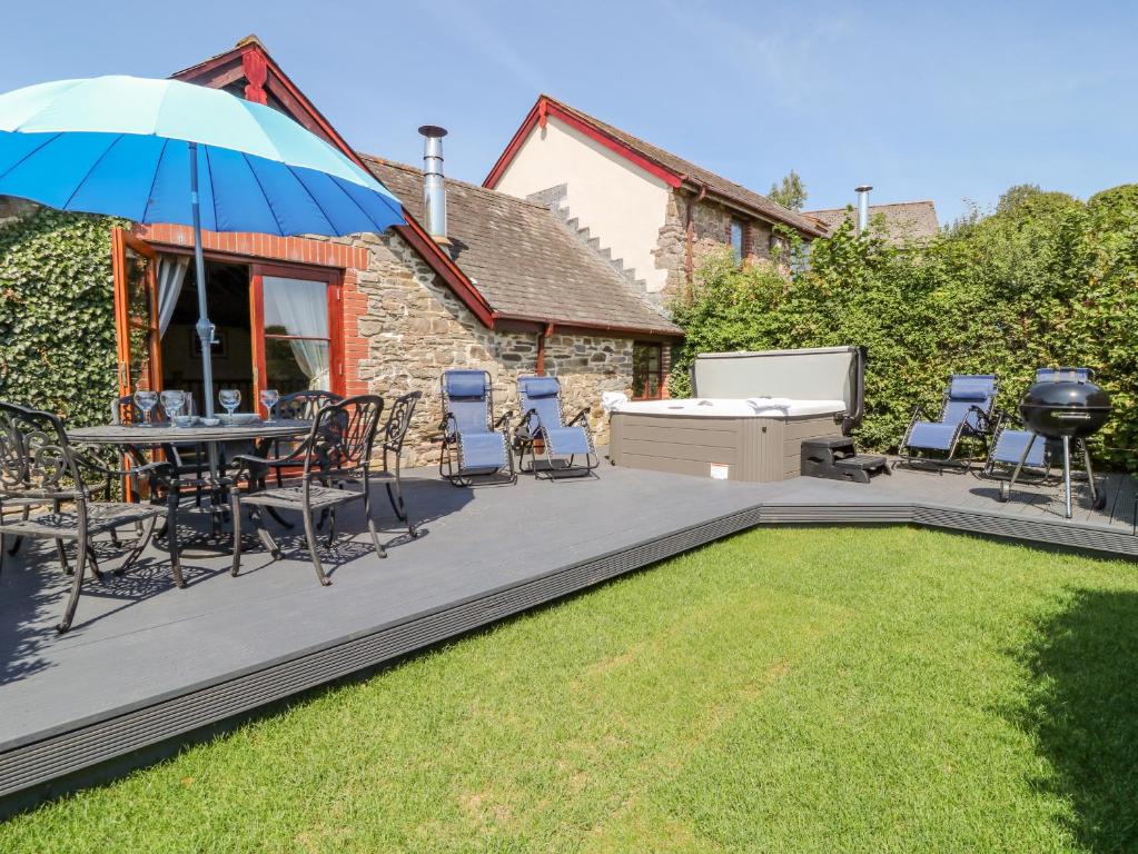 a patio with a table and chairs and an umbrella at Oak Cottage in South Molton