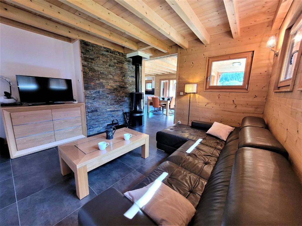 a living room with a leather couch and a tv at Chalet Les Gets, 4 pièces, 6 personnes - FR-1-598-10 in Les Gets