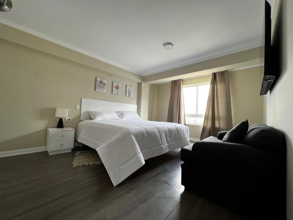 een slaapkamer met een wit bed en een bank bij Departamentos Caraz in Caraz