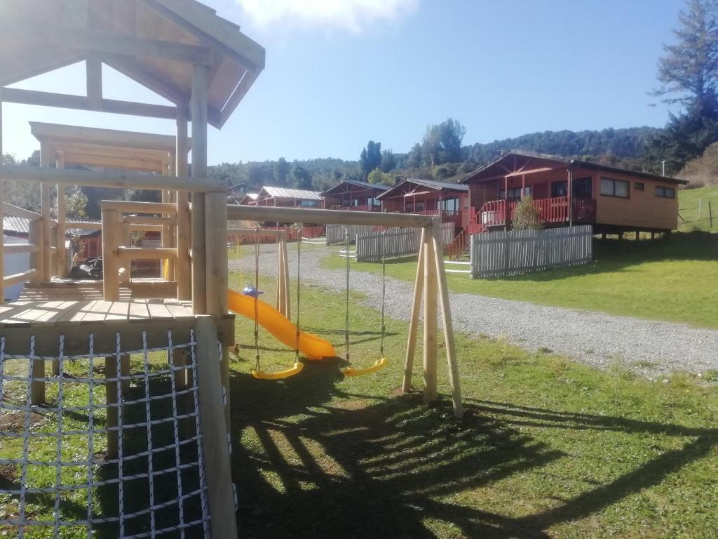 a playground with a slide in the grass at Adilauquen Cabañas y Tinajas Calientes in Puerto Varas