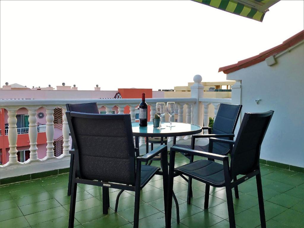een tafel en stoelen op een balkon met een fles wijn bij Acogedor y Luminoso piso con balcón in Arona