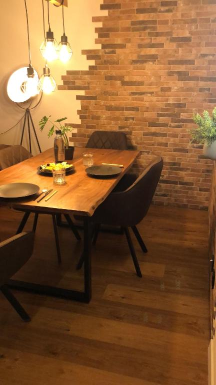 a wooden table and chairs in a room with a brick wall at Luxus Apartment über den Dächern vom Allgäu in Sonthofen