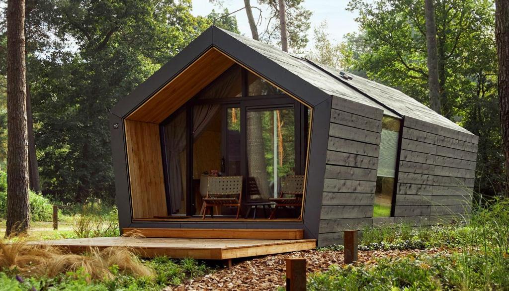 a small black cabin in the woods with a table at Diamond Suite in the woods in Holten