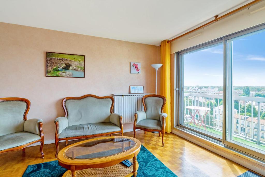 uma sala de estar com cadeiras, uma mesa e uma grande janela em Nice 2 stars apartment with balcony - Vincennes - Welkeys em Vincennes