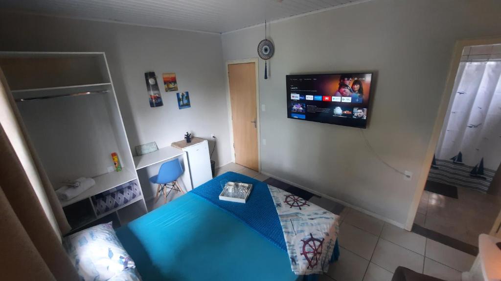 um quarto com uma cama azul e uma televisão de ecrã plano em Suíte Azul com SmartTv, Cama Queen e Banheiro Privativo em Itajaí
