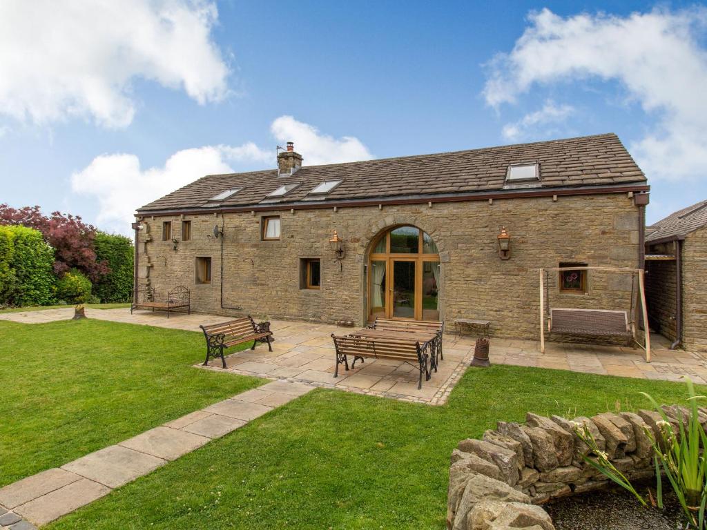 un edificio in pietra con panchine nel cortile di Rough Bank Barn a Rochdale