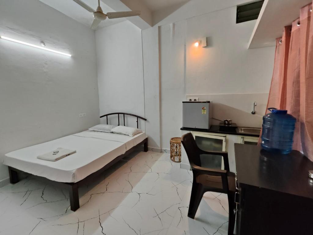 a bedroom with a bed and a table and a kitchen at Mysore Studio Rooms in Mysore