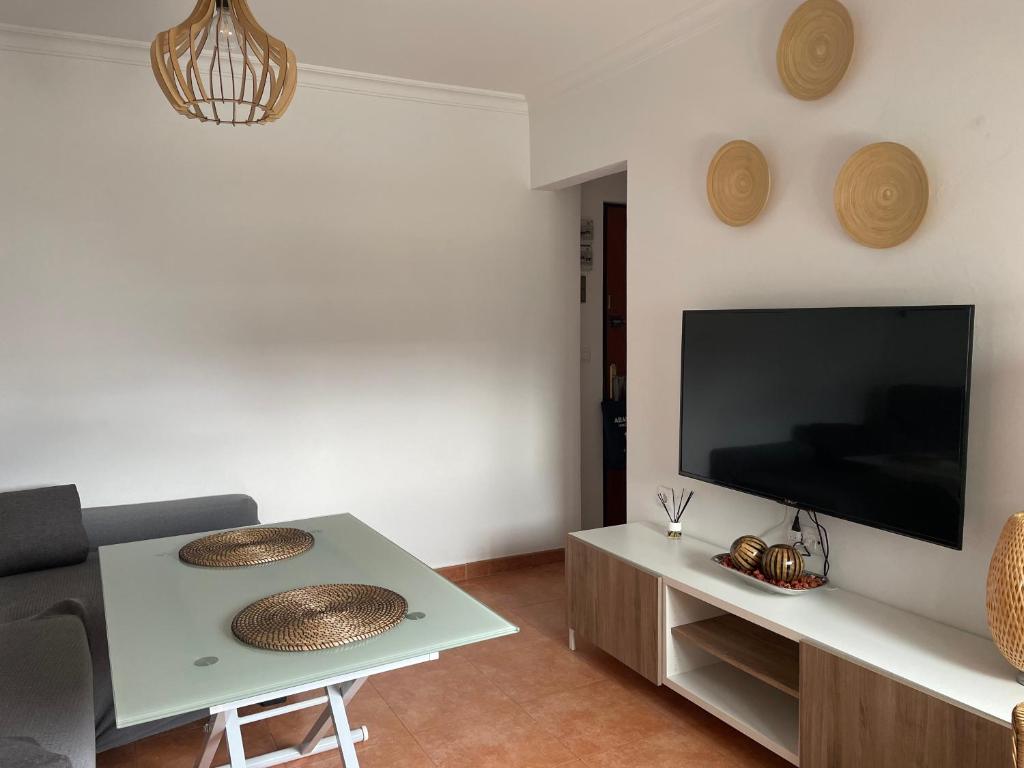 sala de estar con TV y mesa en Apartamento Reina Mercedes Centro-Playa WIFI GRATIS, en Chipiona