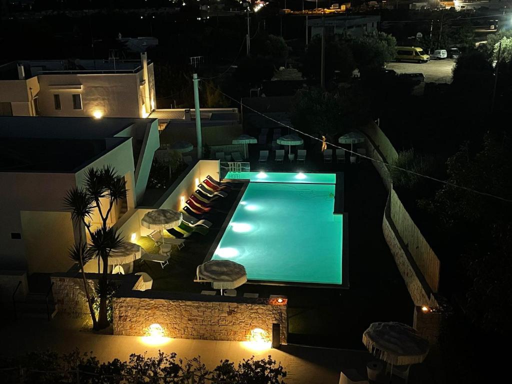 - une piscine avec des chaises et des lumières la nuit dans l'établissement Tuo Hotel, à Polignano a Mare