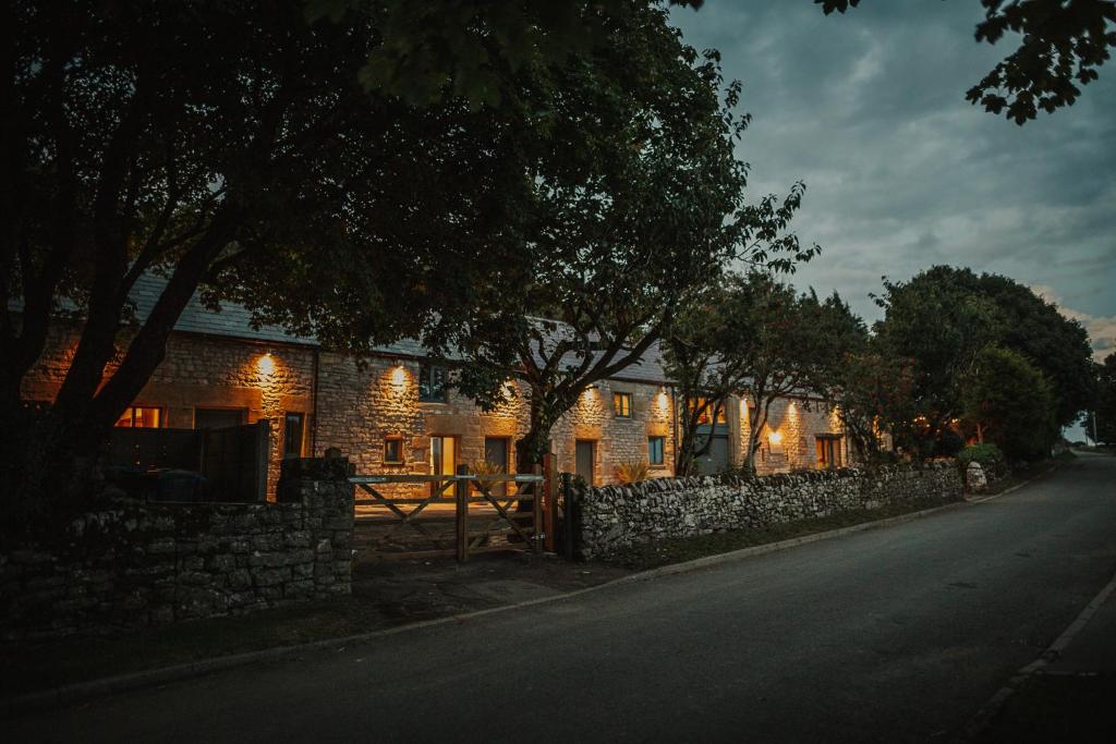 a brick house with a stone wall next to a street at Vicarage Farm Cottages in Tideswell