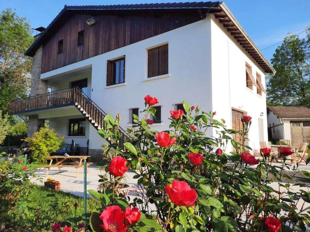 une maison avec des roses rouges devant elle dans l'établissement Le Jardin de Moulis - Maison d'hôtes au pied des Pyrénées, Ariège, Saint Girons, à Moulis