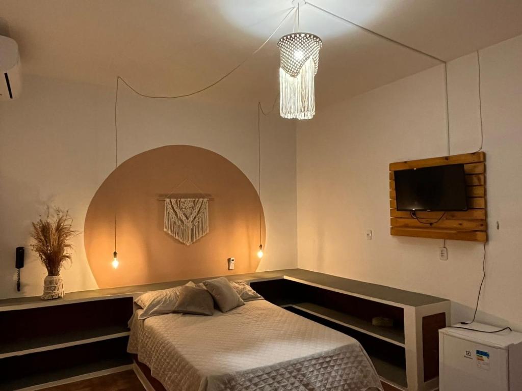 1 dormitorio con 1 cama y TV en la pared en Barra lounge en Maragogi